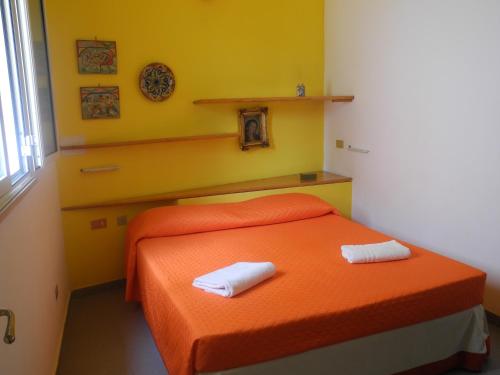 1 dormitorio con 1 cama naranja y 2 toallas en Cala Maluk, en Lampedusa