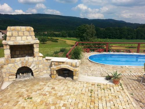 a patio with a stone fireplace next to a swimming pool at Guest House Starý Sedloňov in Trutnov