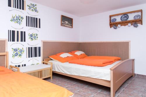two beds in a bedroom with orange pillows at Bence Apartman in Tiszabábolna