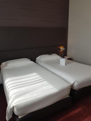 two beds in a room with white sheets at Best Western Plus Hotel Monza e Brianza Palace in Cinisello Balsamo