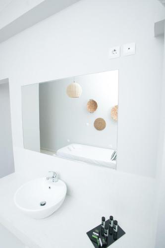 a white bathroom with a sink and a mirror at Akra Morea Hotel & Residences in Monemvasia