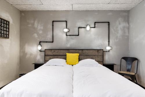 a bedroom with a large bed with a yellow pillow at Upstairs Hotel in Ostend