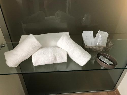 einen Glastisch mit weißen Handtüchern darüber in der Unterkunft Casa Patrizia in Gravellona Toce