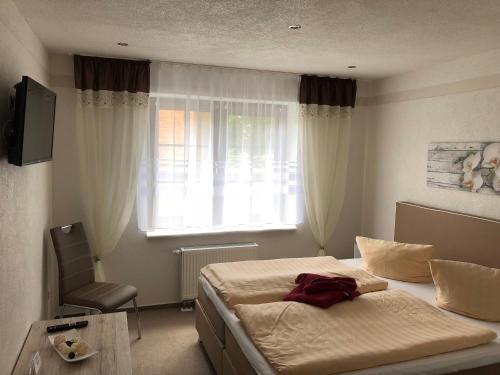 1 dormitorio con cama, ventana y silla en Pension & Gasthof Storchennest, en Groß Quassow