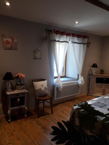 a bedroom with a bed and a window with a chair at Chambres d hôtes Le clos des vins d anges in Saint-Pierre-des-Champs