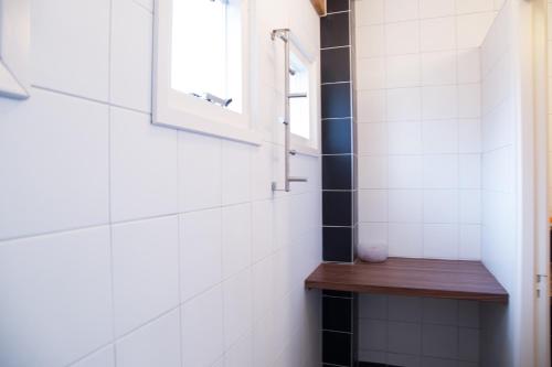 a bathroom with white tiled walls and a wooden shelf at B&B "de Wingerd" in Bruchterveld
