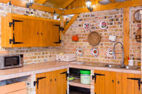 a kitchen with wooden cabinets and a brick wall at Bence Apartman in Tiszabábolna