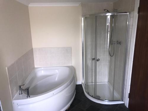 a white bathroom with a shower and a toilet at Smithyends Apartments in Cumbernauld