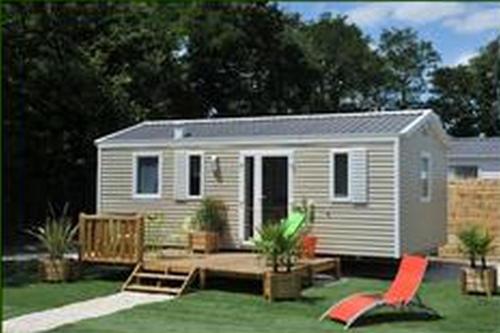 a tiny house with a porch and a deck at Camping Au Bord de l'Aisne in Guignicourt