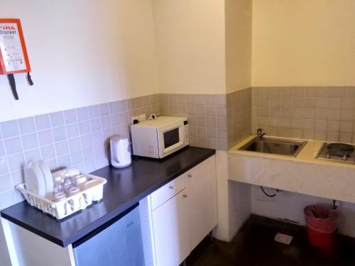 a small kitchen with a microwave and a sink at Beit Al Ward in Ash Shafa