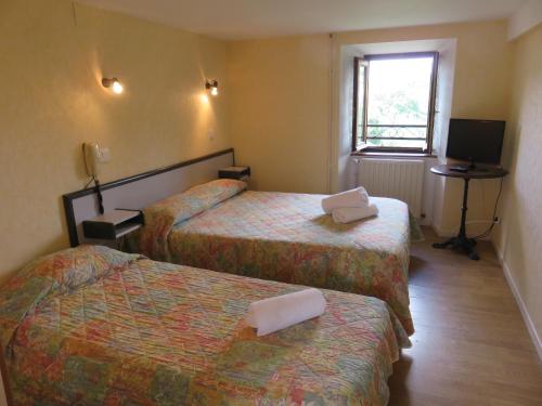a hotel room with two beds and a television at Hôtel Le Bel Air in Lanuéjols