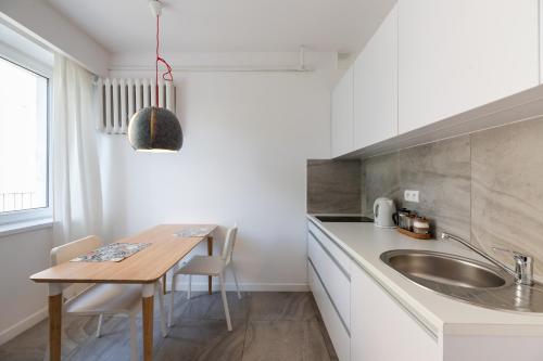 uma cozinha com uma mesa de madeira e um lavatório em Apartament w sercu miasta em Łódź