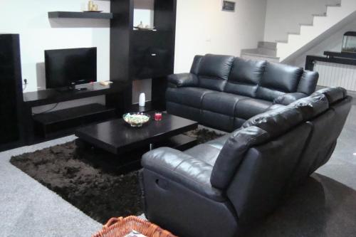 a black leather couch and a coffee table in a living room at Casa do Nascente in Paredes do Rio