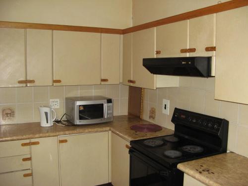 a kitchen with a stove and a microwave at Johannesburg Boarding Hostel in Johannesburg