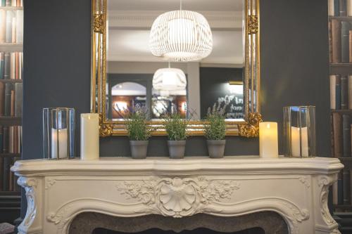a mantel with candles and potted plants in front of a mirror at George Hotel, BW Signature Collection in Norwich