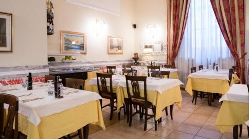 ミラノにあるHotel Siciliaのテーブルと椅子(黄色と白のテーブル付)のあるレストラン
