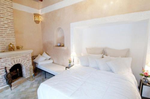 a bedroom with a white bed and a fireplace at Riad Palais Des Princesses & Spa in Marrakesh