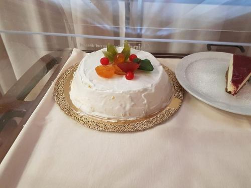 a white cake with fruit on top on a table at Hotel Sicilia in Milan