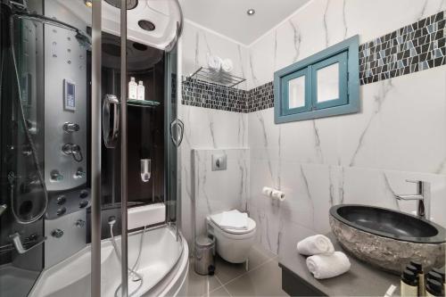 a bathroom with a tub and a sink and a toilet at Royal Villa Pedi in Symi