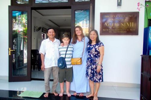 a family posing for a picture in front of a building at Ngọc Sinh Homestay in Hoi An
