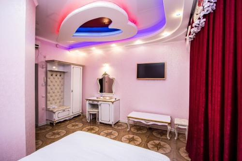 a room with a bed and a tv and a red curtain at Hotel Zamok Korolya in Voronezh