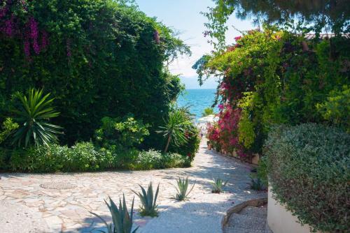 a walkway with plants and the ocean in the background at Bougainvill Sunset Villa in Sarandë