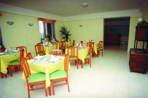 ein Esszimmer mit Tischen und Stühlen sowie gelben Tischen und Stühlen in der Unterkunft Szamárkút Panzió in Pécs