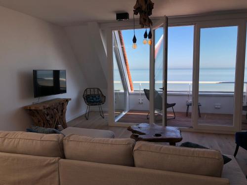 a living room with a couch and a view of the ocean at Penthouse in Badhuis Cadzand in Cadzand