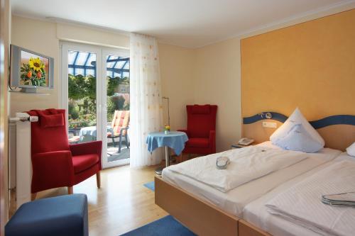 a bedroom with a bed and two chairs and a table at Hotel Meschenmoser in Langenargen
