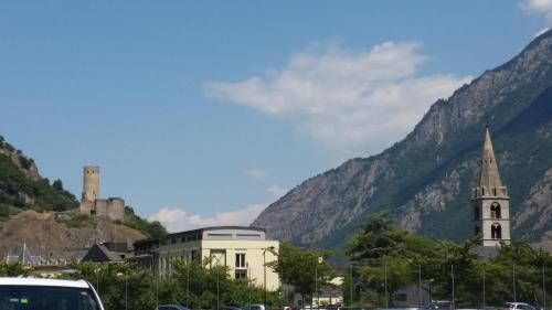 a building and a church in front of a mountain at Motel des Sports Martigny in Martigny-Ville