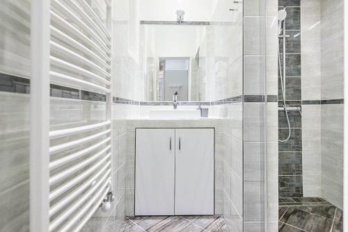 uma casa de banho branca com um lavatório e um chuveiro em Dominik Apartment em Budapeste