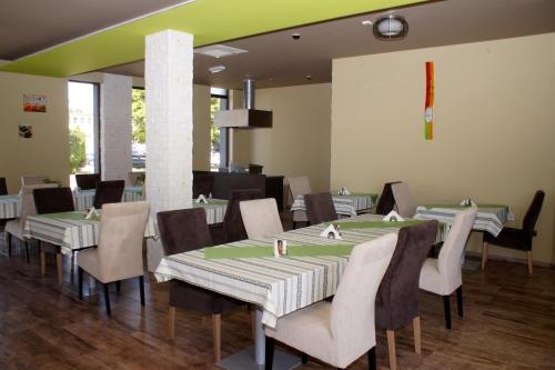a dining room with green and white tables and chairs at Fitromax Sportpanzió Ajka in Ajka