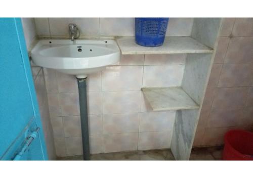 La salle de bains est pourvue d'un lavabo blanc et d'étagères. dans l'établissement Shri Shyam Krishna Guest House, à Pushkar