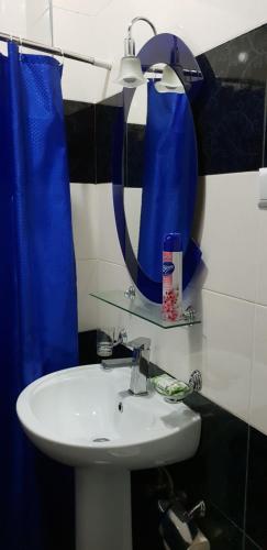 a bathroom with a white sink and a blue shower curtain at Apartment Rustaveli 59 in Batumi