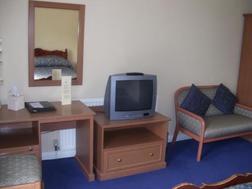a living room with a tv, couch and chair at Barn Hotel London Ruislip in Hillingdon