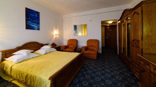 una camera d'albergo con un letto e due sedie di Hotel Decebal a Bacău