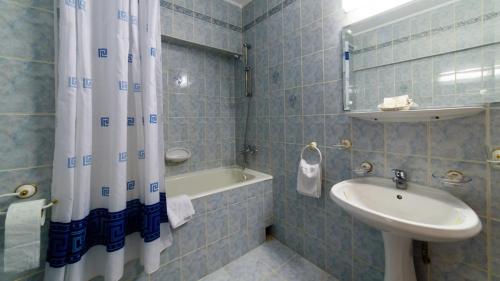 a bathroom with a sink and a shower curtain at Hotel Decebal in Bacău