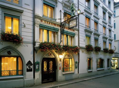 a building on a street with flowers on it at Romantik Hotel Wilden Mann Luzern in Lucerne