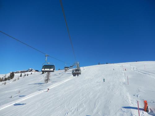 a ski lift with people skiing down a snow covered slope at Haus am Wald in Steindorf am Ossiacher See