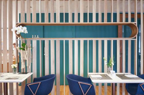 a dining room with two tables and blue chairs at Lasala Plaza Hotel - Adults Only in Donostia-San Sebastián