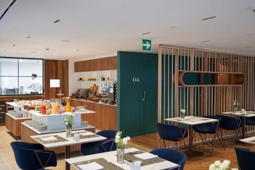 a dining room with tables and chairs and a kitchen at Lasala Plaza Hotel - Adults Only in Donostia-San Sebastián