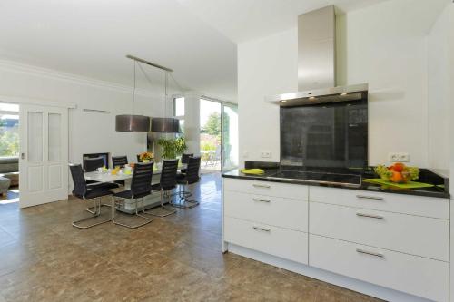 una cocina con armarios blancos y una mesa con sillas. en Lotsenstieg 11 en Ostseebad Karlshagen