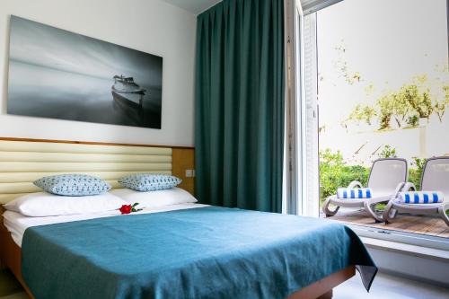 a bedroom with a bed and a large window at Hotel Laguna - Terme Krka in Strunjan