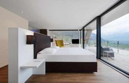 a bedroom with a white bed and a large window at B&B Boutique Hotel Burgund in Parcines