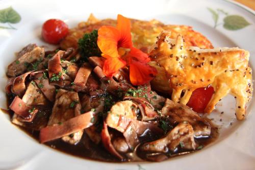 a white plate of food with meat and vegetables at Hotel & Spezialitätenrestaurant zur Linde in Teufen