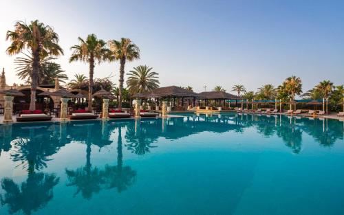 a large pool of blue water with palm trees at Africa Jade Thalasso in Korba