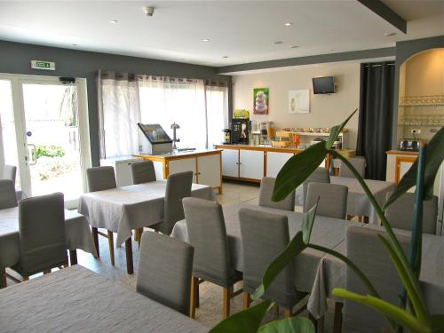 een wachtkamer met tafels en stoelen en een keuken bij Hôtel Restaurant L' Empereur in Aléria