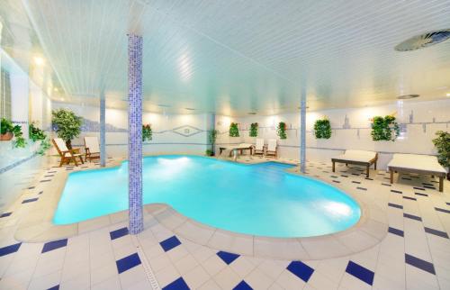 een groot zwembad in een kamer met tafels en stoelen bij Hotel Spindlerova Bouda in Špindlerův Mlýn