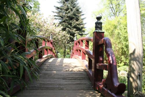 a red bridge in a park with trees at Kasino Hotel in Leverkusen