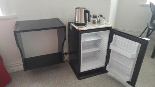 a small refrigerator with its door open next to a table at Guesthouse Sólgardar in Akureyri